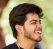 Smiling young indian man portrait in black t shirt and silver neck chain outdoor green public park