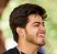 Smiling young indian man portrait in black t shirt and silver neck chain outdoor green public park